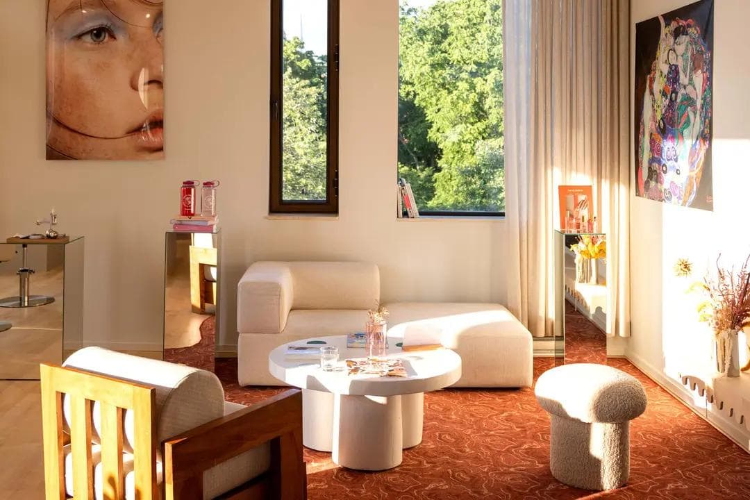 Beauty and wellness spots in Montreal’s Mile End, including serene facial rooms at Beauties Lab with white sofas and park views, vibrant fuchsia seating for luxury pedicures at Lio Fratelli, the bright orange-and-white interiors of Ten Spot, the sleek white-brick salon of Orbite with high-end hair products, and Espace Nomad’s tranquil treatment rooms for massages and holistic care.